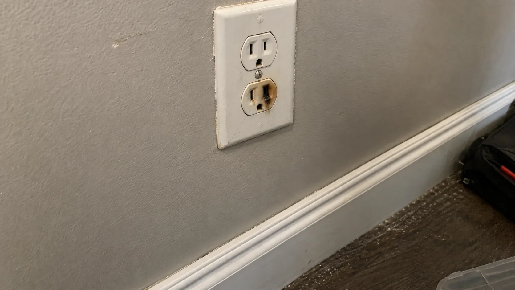 Residential electrical outlet showing heat damage and discolouration around the socket