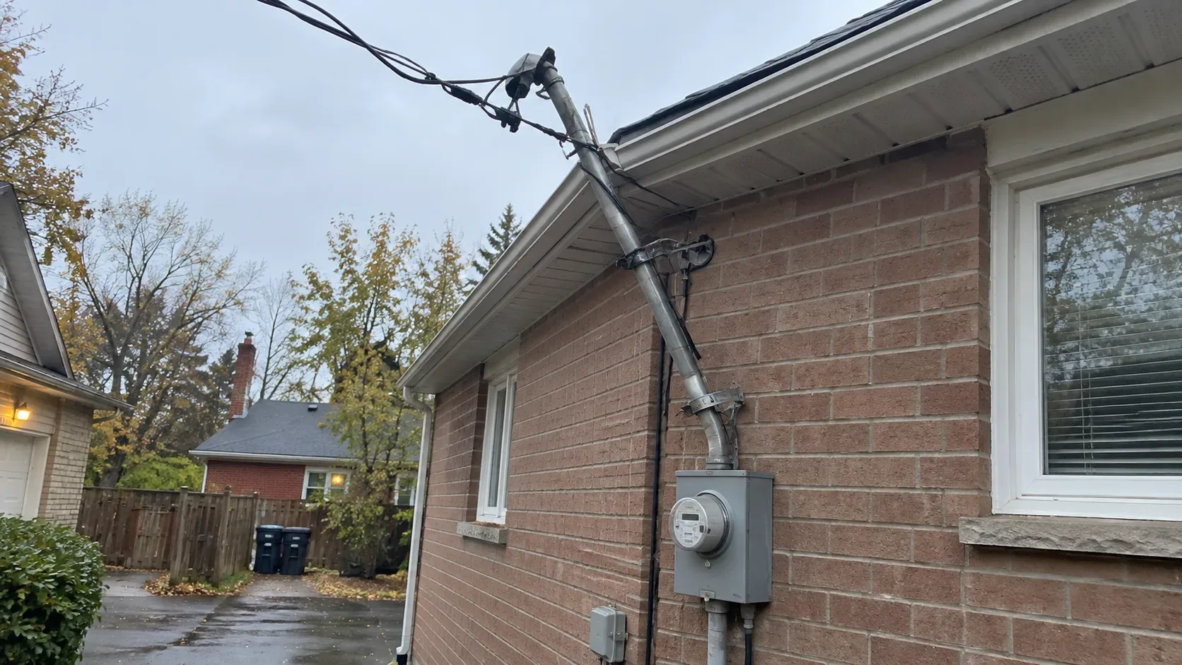 Storm-damaged exterior electrical service equipment on a Canadian residential house